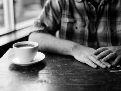 Person sitting at table with a cup of coffee in front of them