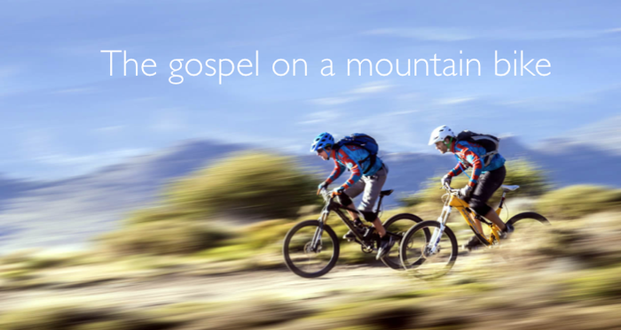 Two people on mountain bikes riding down a hill